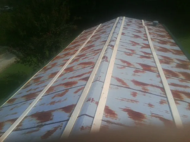 Rusted metal roof panels with new wood purlins before replacement in Zionsville