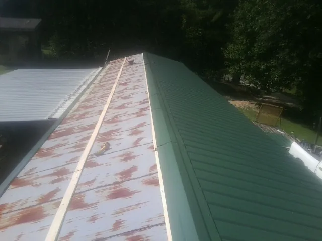 Old rusted panels beside newly installed green metal roofing — Wind Damage Roof Repair by Roofing Brothers in Zionsville