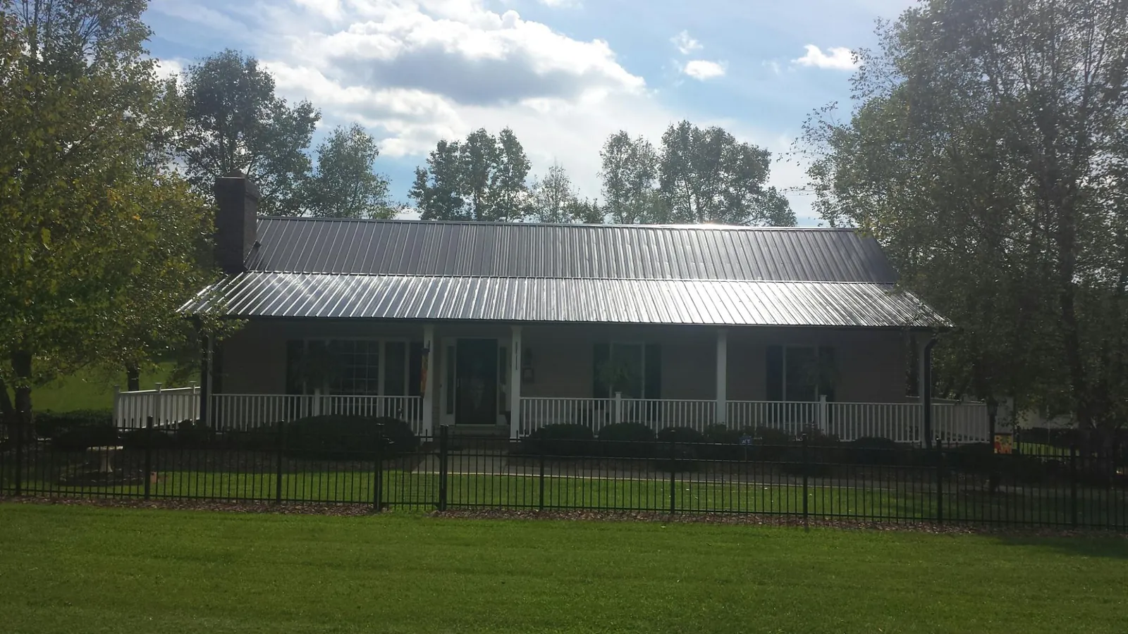 Gray metal roof on a brick ranch with a full width front porch — Gutter Guard Installation work by our crew in Zionsville