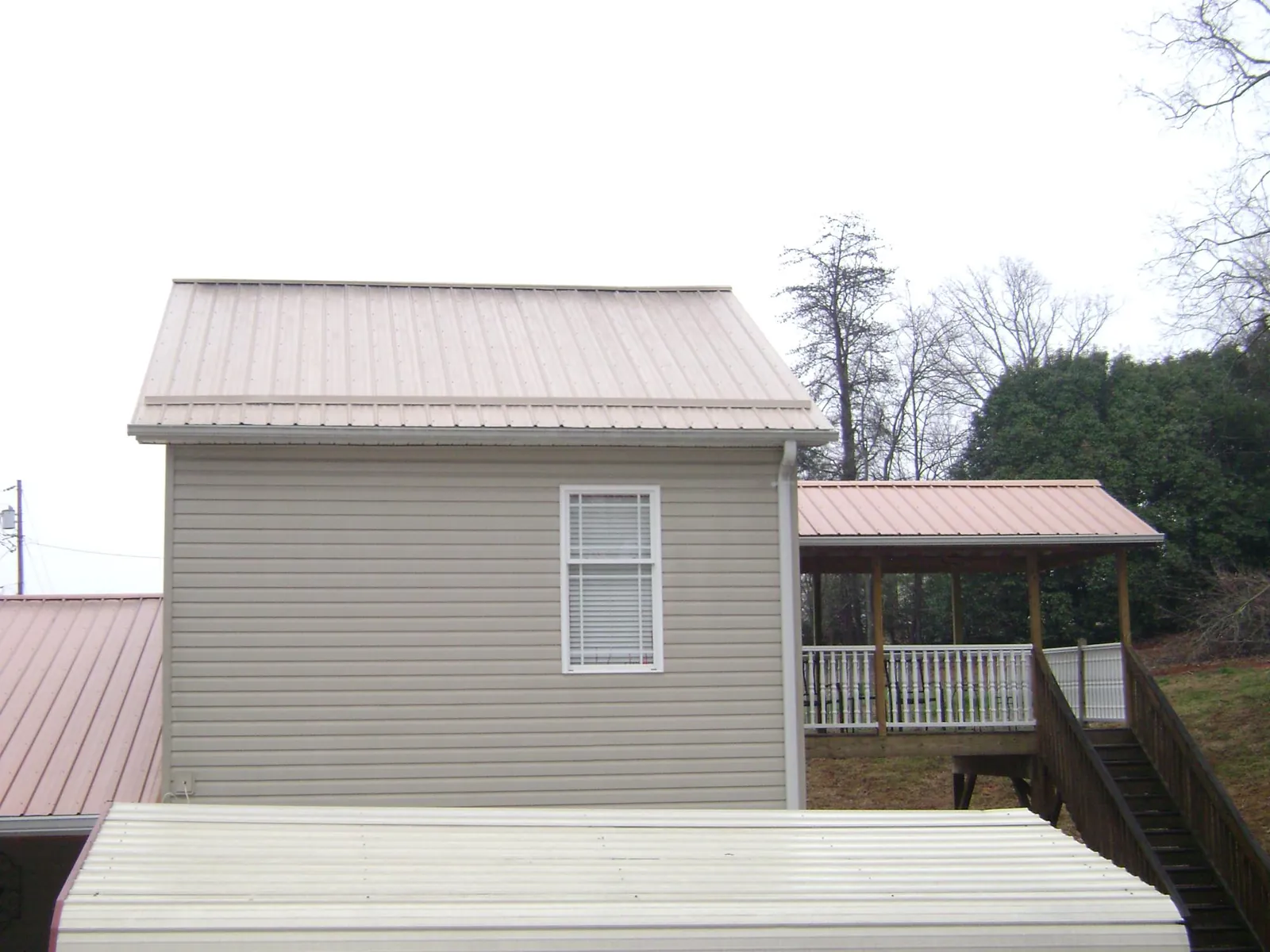 Tan metal roofs on a two story addition and attached porch, from a Roof Replacement job in Zionsville