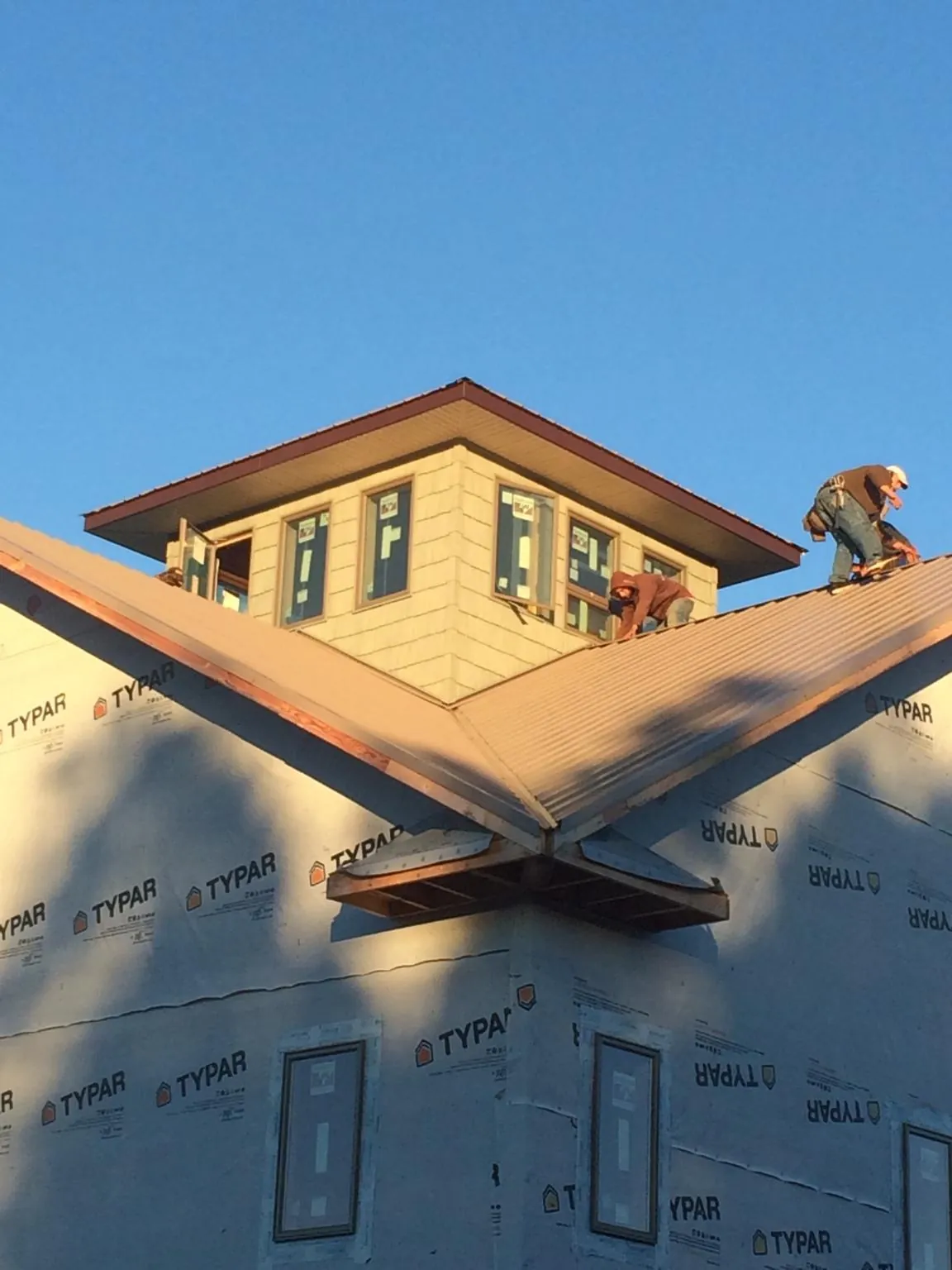 Roofers working around a rooftop cupola on a new metal roof at sunset — Roof Waterproofing in Zionsville by Roofing Brothers